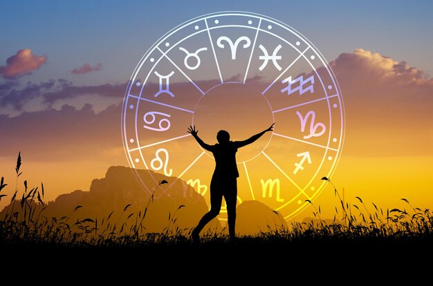 Silhouette of person with raised arms under zodiac signs at sunrise, symbolizing horoscope guidance and positivity